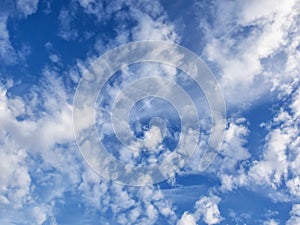 White, puffy clouds in blue sky with jet and con trail