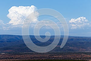 White puffy Clouds over the dry mountain land