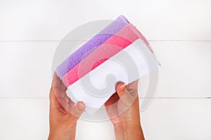 White, purple and pink towels in hands on a white wooden table.
