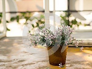 White and purple plastic flowers in vase decorative table outside home. Home design