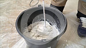 White putty cement in black bucket on floor for rebuild wall at home - can use to display or montage on product. White mixture in