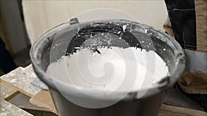 White putty cement in black bucket on floor for rebuild wall at home - can use to display or montage on product. White mixture in