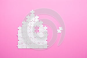 White puzzle. House shape puzzle. The concept of rent, mortgage. Pink background. Top view