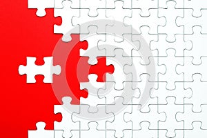 White puzzle pieces on a red background separated