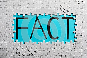 White puzzle pieces and word FACT written on light blue background, flat lay