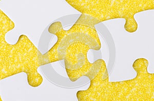 White puzzle pieces on yellow textured surface
