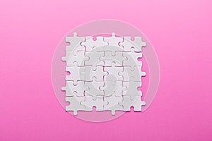 White puzzle on pink background. Top view