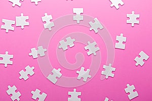 White puzzle on pink background. Top view