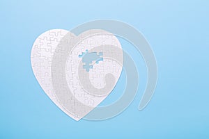 White puzzle in shape of heart on blue background Jigsaw Concept treatment of heart disease pills