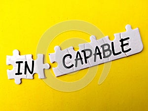 White puzzle with the word INCAPABLE on a yellow background