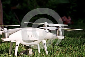 White quadcopter Drone with 4K digital camera on grass is ready for take off to fly in air to take photos, record footage.