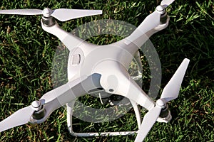 White quadcopter Drone with 4K digital camera on grass is ready for take off to fly in air to take photos, record footage.