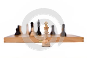 White Queen chess piece in front of burry chess board on white background