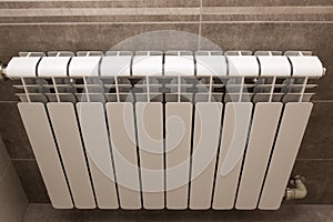 White radiator in the bathroom close-up. Heating. Tiled gray wall.