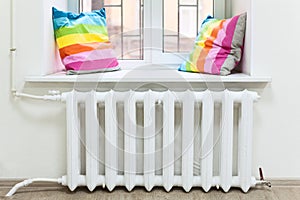 White radiator of central heating in domestic room under window