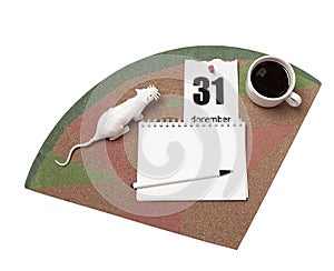 A white rat, a calendar sheet, coffee and a notebook with a pen on a cork Board.