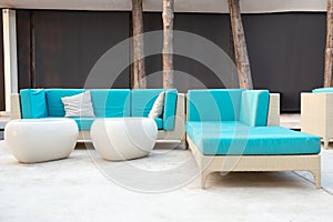 White rattan garden furniture with blue cushion on resort terrace.