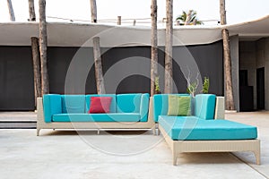 White rattan garden furniture with blue cushion on resort terrace.