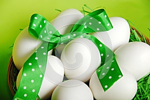 White raw eggs with jolly green ribbons and spring green background