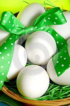 White raw eggs with jolly green ribbons and spring green background