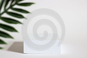 White rectangular box with shadows on a light white background. For cosmetics or cosmetology background. stand for advertising bea