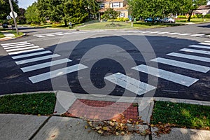 White rectangular intermittent crosswalk markers painted on the asphalt road in a residential neighborhood