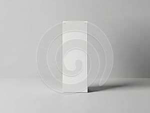 A white rectangular object stands upright on a plain gray surface with subtle shadow