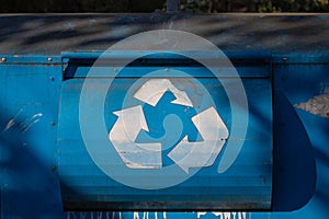 White recycling sign on the blue recycle bin