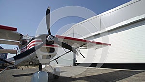 White and red airplane near of hangar