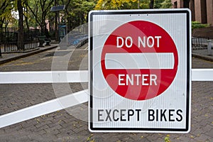 White red black street sign reading do not enter except bikes