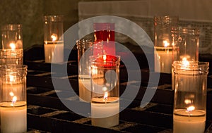 White and red candles in church. Glowing candles with burning flame. Faith and religion concept. Church decoration.