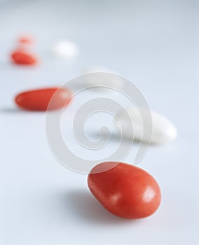 White and red candy-coated almonds still life composition imitating steps