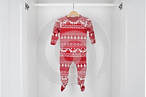 White and red christmas pajamas hanging on a wooden hanger in the middle of a white closet