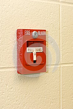 White and red fire alarm on a stone wall under the lights