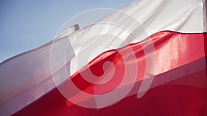 White and red flags seen from very close up wave in the summer wind. The flag of the Polish state.