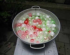 White, red and green mini water balloons in tin bucket