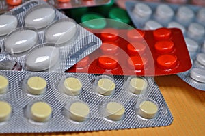 White, red, green round and oval medical tablets in pack, tablets packed in blisters closeup