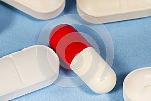 White and red hard gelatin capsule beside other drugs