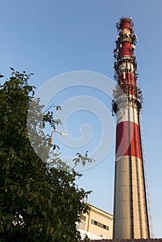 White-red industrial chimney with antennas