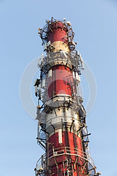 White-red industrial chimney with antennas