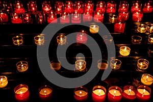 White and red lit candles in church in darkness