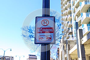 A white and red no parking sign on a black pole surrounded by buildings with balconies at Atlantic Station photo