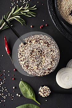 white and red quinoa grits with spices in a black bowl, top view