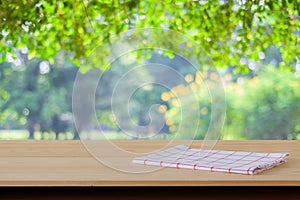 White and red tartan cloth on wood table over blur garden background