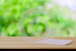 White and red tartan cloth on wood table over blur garden background