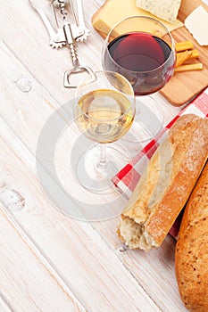 White and red wine, cheese and bread on white wooden table background