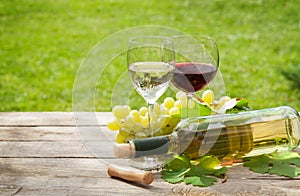 White and red wine glasses and bottle with bunch of grapes