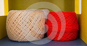 White and red yarn ball resting on shelf