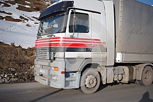 White refrigerated truck on winter road on background of the mountains