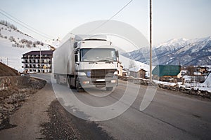 White refrigerated truck on winter road on background of the mountains